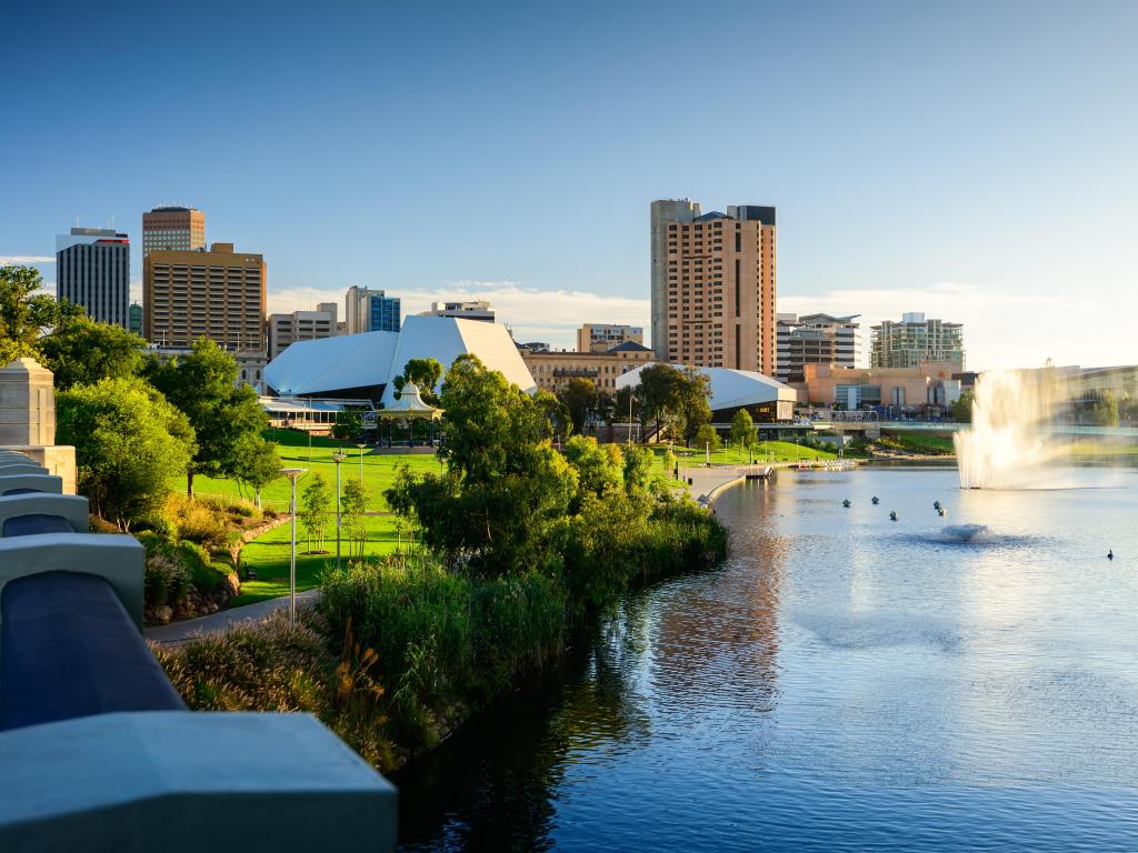 Green lawns, trees and tall buildings beside a lake