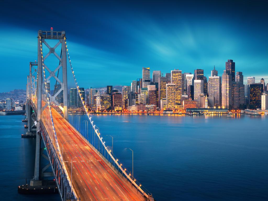 San Francisco, California, USA at sunrise with Bay Bridge in foreground and the city skyline in the distance.