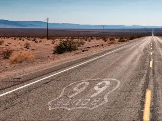 Panoramic view of Route 66 road to Joshua Tree National Park on a sunny day, with mountains in the background