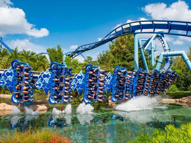 Up close shot of people riding and having fun on the bright blue Manta Ray rollercoaster in action at Seaworld 