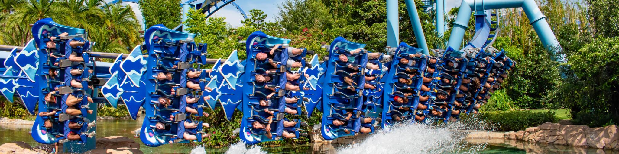 Up close shot of people riding and having fun on the bright blue Manta Ray rollercoaster in action at Seaworld 