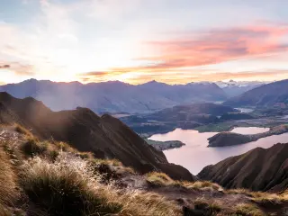 Queenstown, New Zealand with a panorama at sunset of Roys Peak between Wanaka and Queenstown with a lake and mount aspiring and cook of the new zealand alps on the background