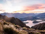 Queenstown, New Zealand with a panorama at sunset of Roys Peak between Wanaka and Queenstown with a lake and mount aspiring and cook of the new zealand alps on the background