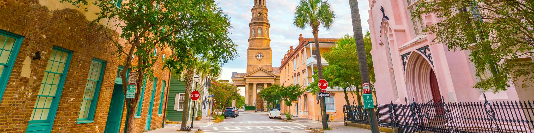 A scenic road with fascinating old buildings in pink, orange, green, and powder blue at twilight in the historic downtown of Charleston, South Carolina 