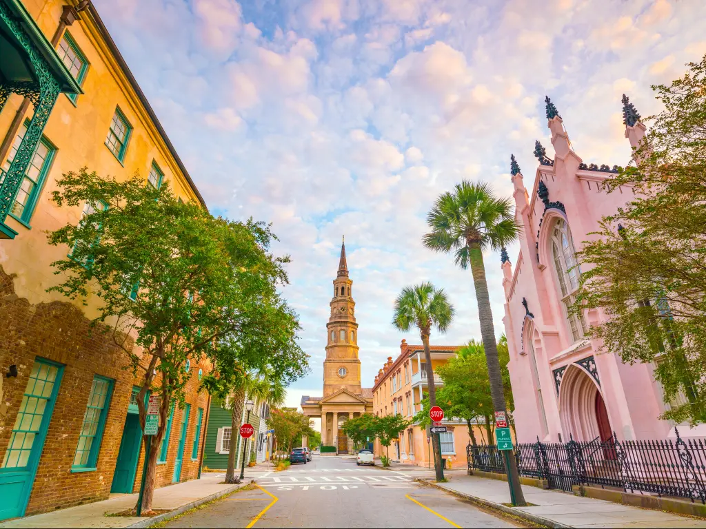 A scenic road with fascinating old buildings in pink, orange, green, and powder blue at twilight in the historic downtown of Charleston, South Carolina 