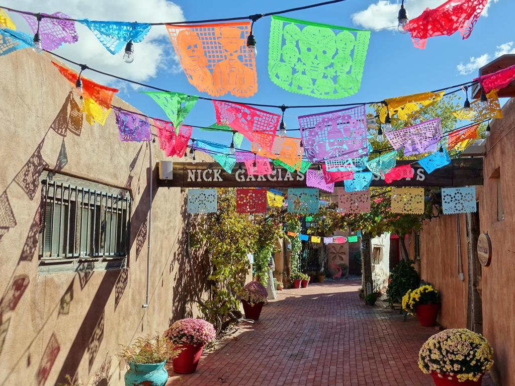 Brightly coloured little flags strung out across historic street with tiled path and plaster covered buildings