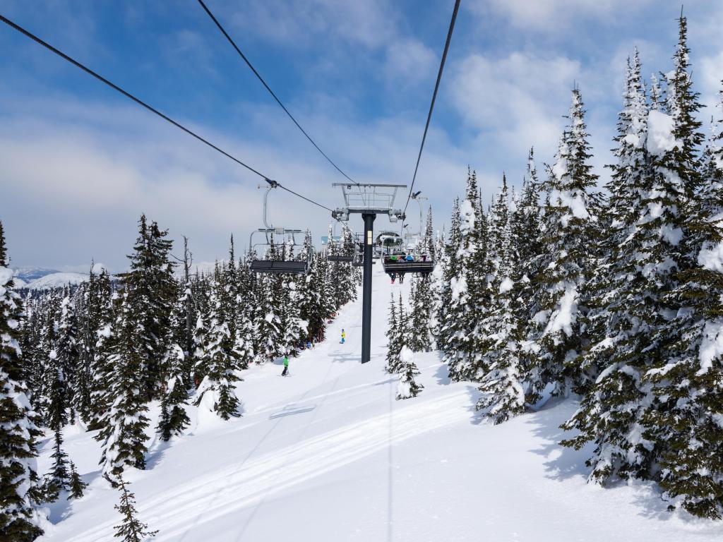 Ski chairlift going up a ski slope in the snowy mountain range of Big Mountain in Whitefish, Montana