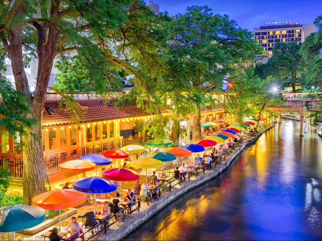 People eating dinner at tables set along the River Walk in San Antonio, Texas.