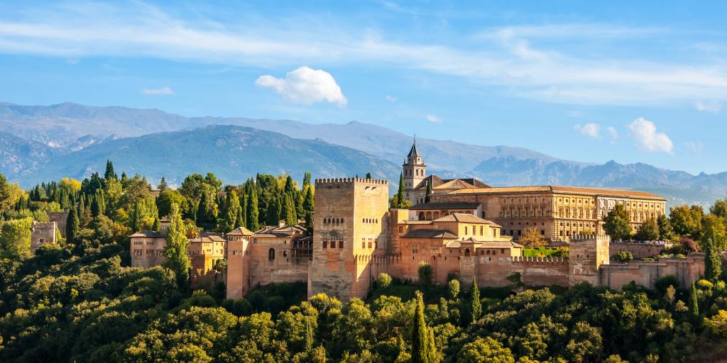 Aerial view of Alhambra Palace in Granada, Spain with Sierra Nevada mountains in the background, on a sunny day