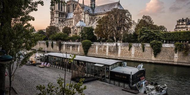 La Nouvelle Seine barge floats on the river in Paris in front of the Notre Dame