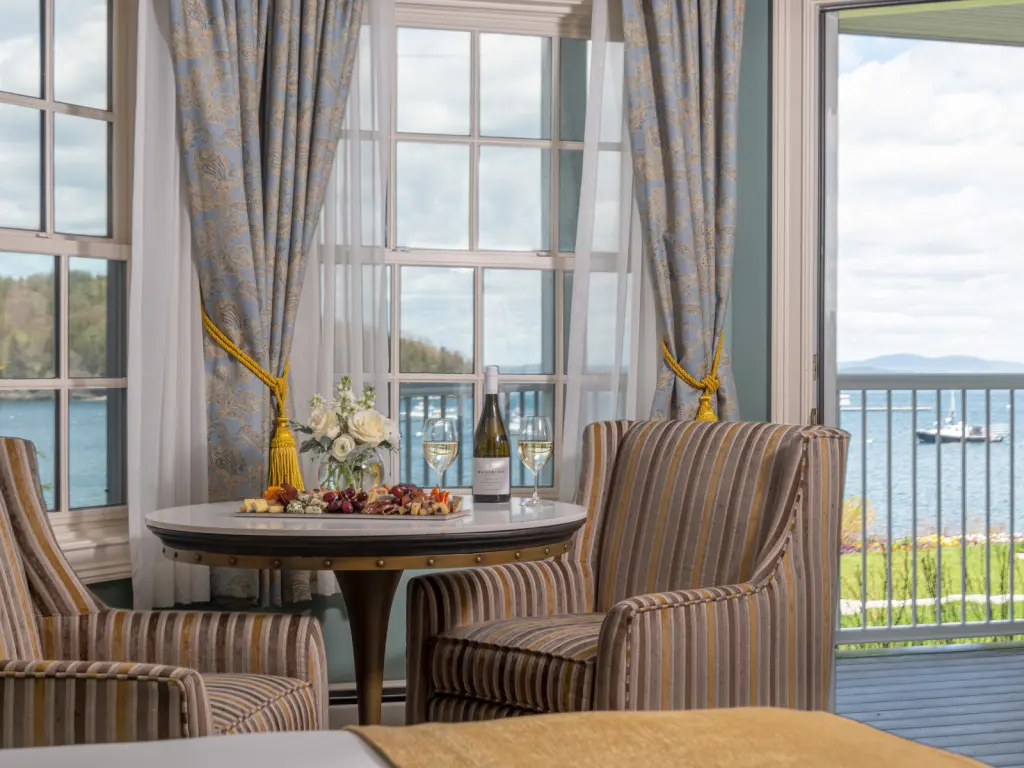 Interior of a hotel room with ocean views out of the window, wine and snacks places on a table 