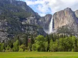 View of Bridalveil Fall with forests in the foreground, and blue skies overhead