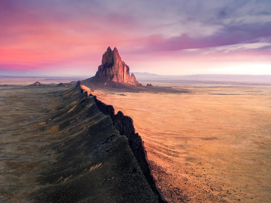 Ship Rock Navajo with buckled terrain casting shadows, New Mexico, with purple sunset sky above
