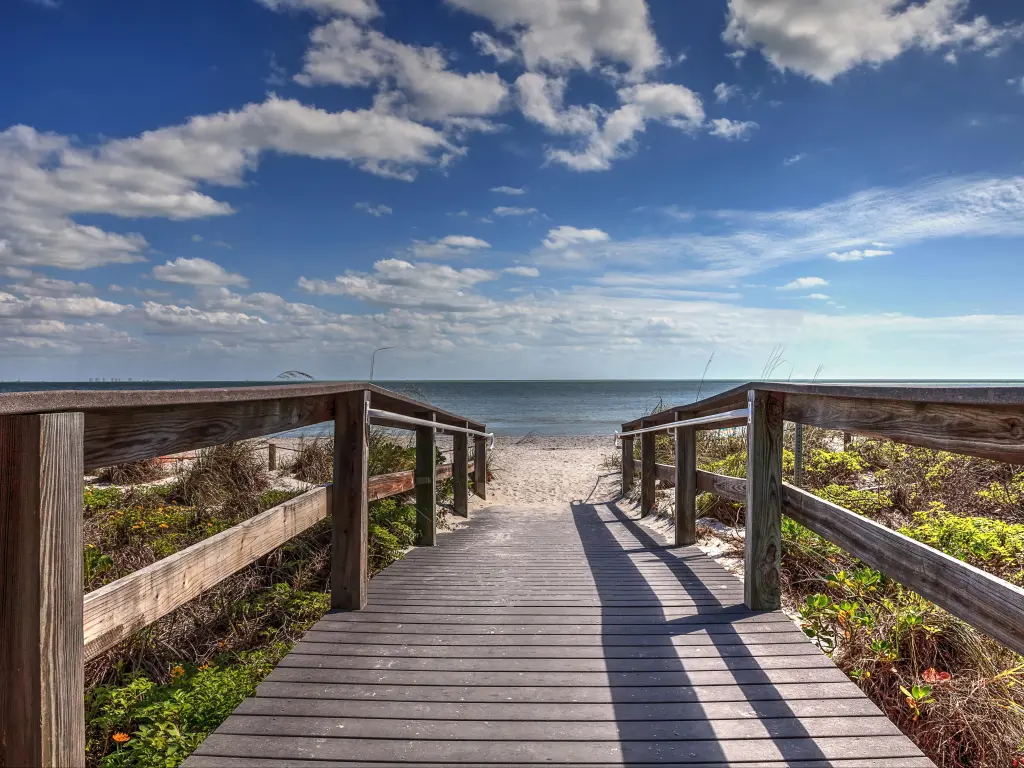 Boardwalk leading to Lighthouse Beach Park in Sanibel, Florida under a blue sky.