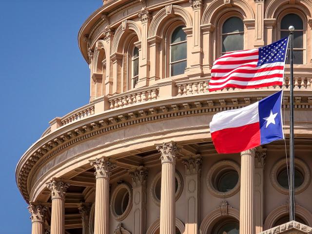 American and Texas State flags flying at the Texas State Capitol building in Austin