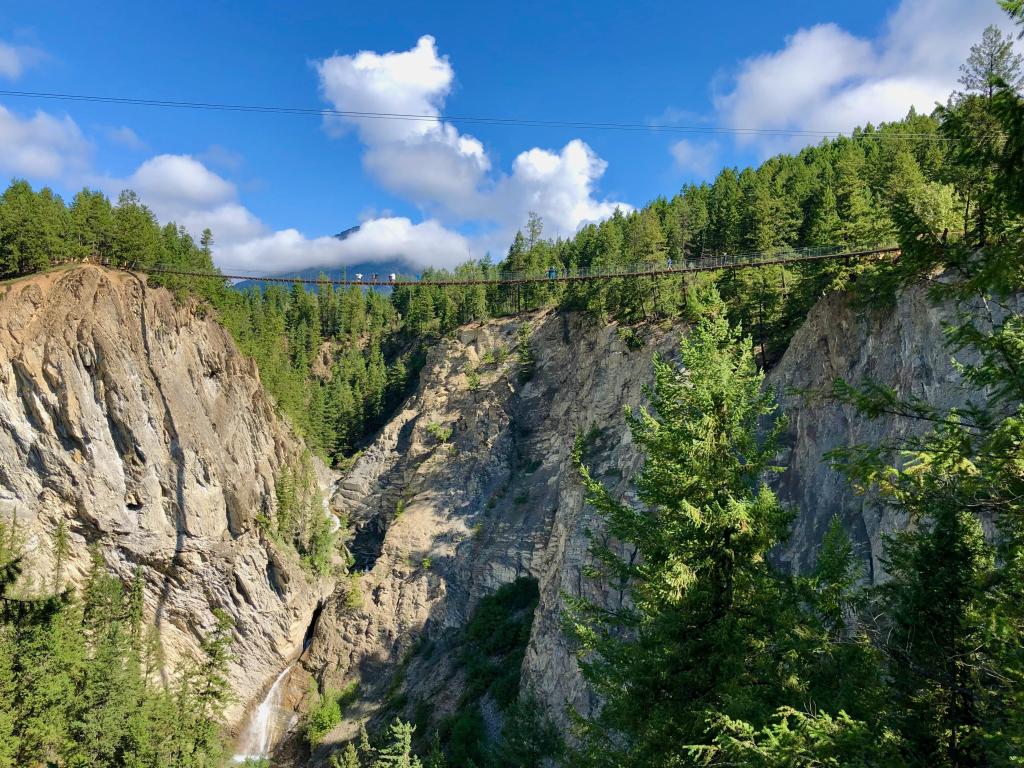 Golden Skybridge, Golden, BC, Canada with a view of the suspension bridge and of people using it to cross the canyons on a sunny day.