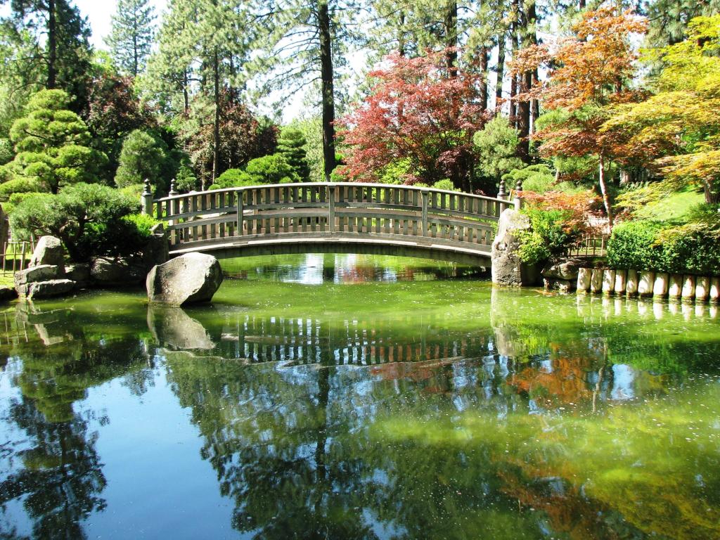 Ornate stone bridge crossing a small body of water with autumn foliage reflected in a calm lake 