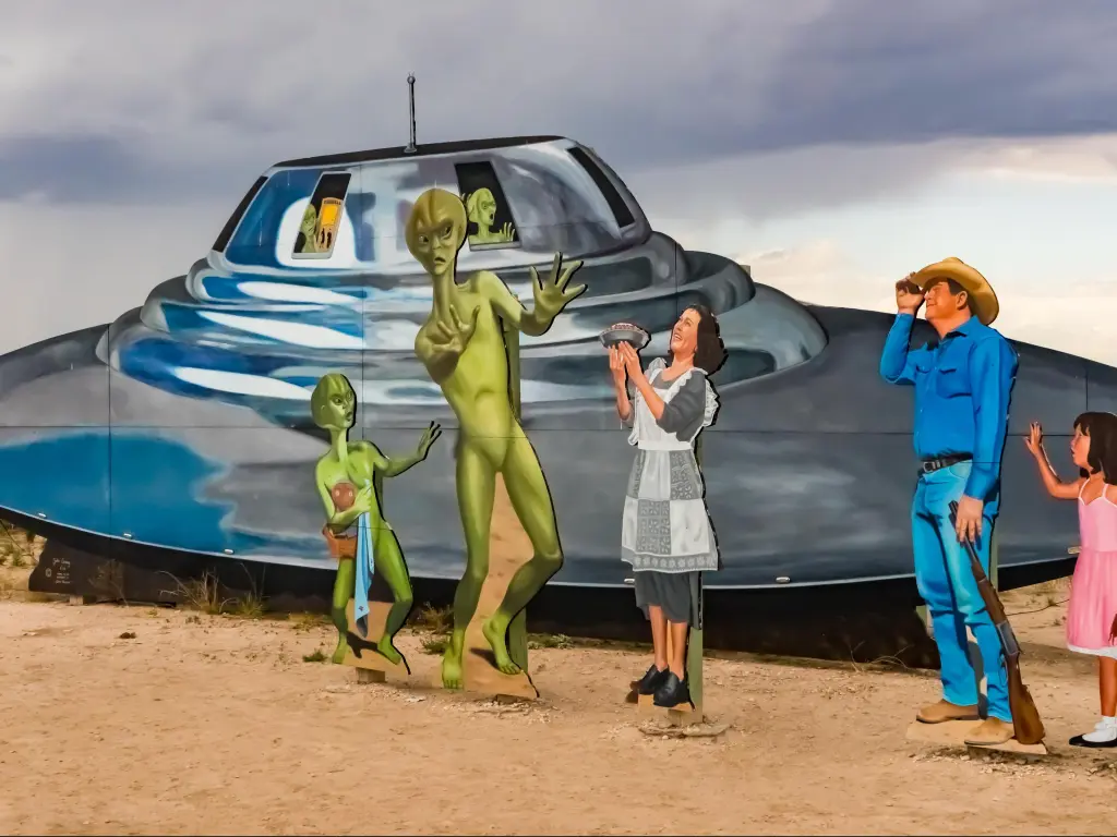 Roswell, New Mexico welcome sign cutouts with a alien and human family encounter, and a flying saucer spaceship.