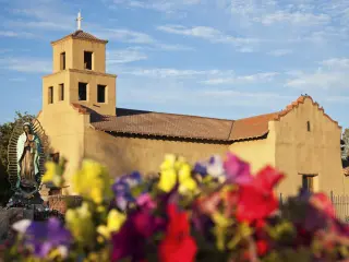 Sanctuary Of Guadalupe on a cloudy day with colorful flowers in the foreground