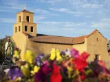 Sanctuary Of Guadalupe on a cloudy day with colorful flowers in the foreground