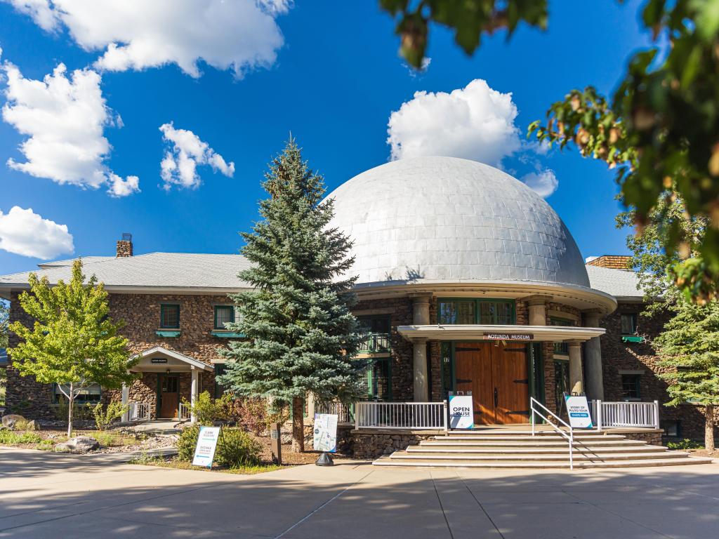 Famous observatory's facade and white dome, framed by trees, on a sunny day witha few clouds
