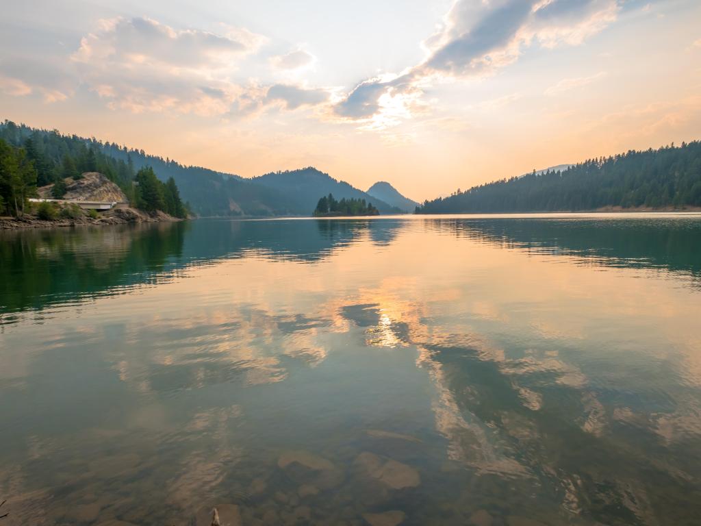 Sun setting over Rimrock Lake surrounded by evergreen trees