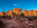 Bright sunlight illuminating the beautiful Skyline Arch sandstone rock formation at golden hour, Arches National Park, Moab, Utah