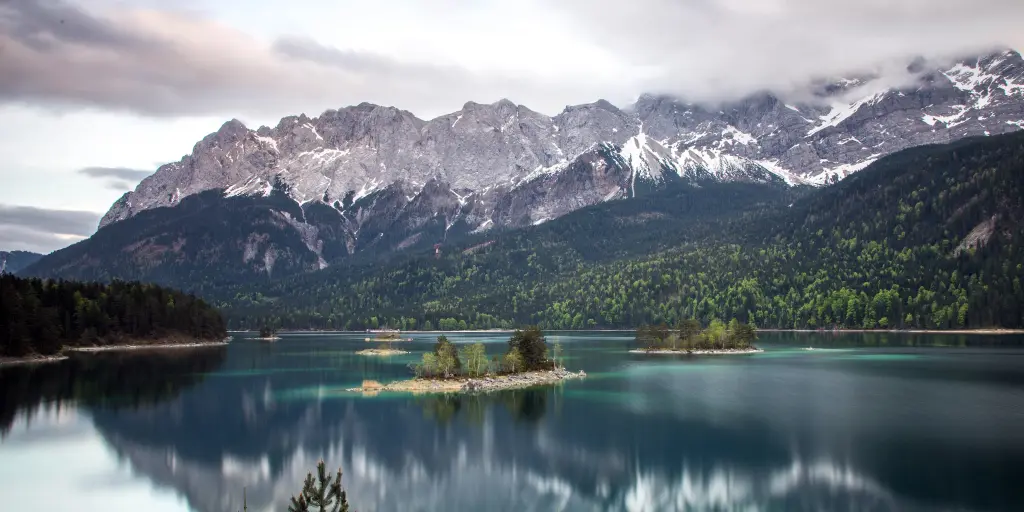 Snow-capped mountains reflect on the surface of Lake Eibsee in Garmisch-Partenkirchen, Bavaria