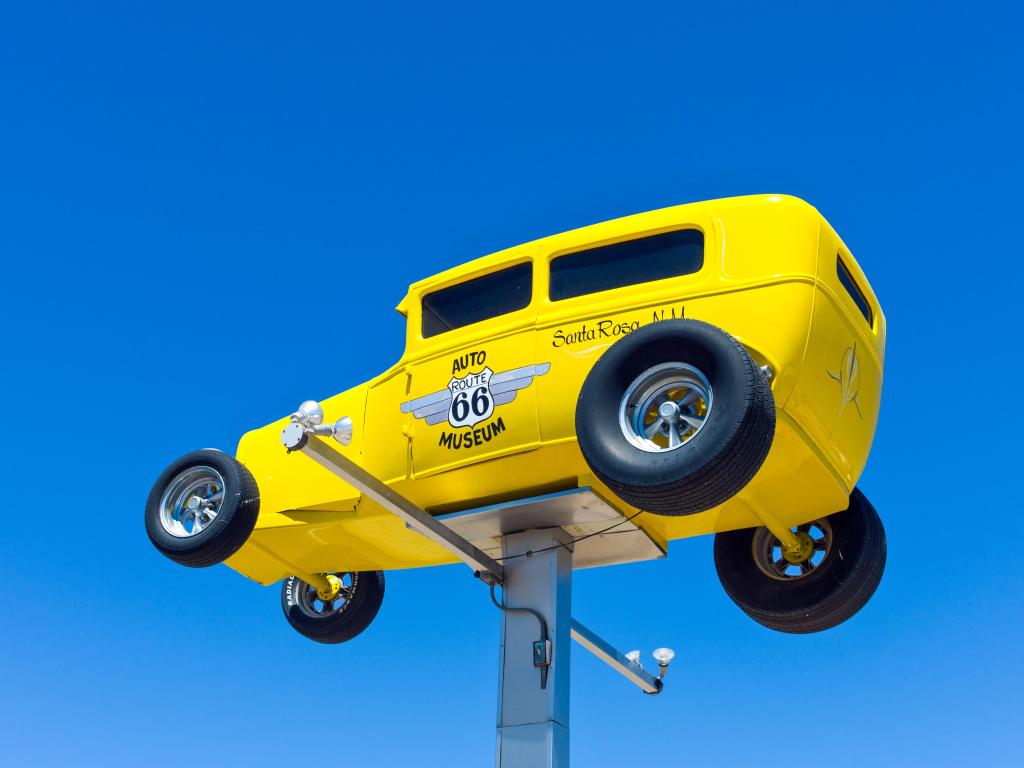 The museum's sign, a yellow car, on a sunny day with blue sky
