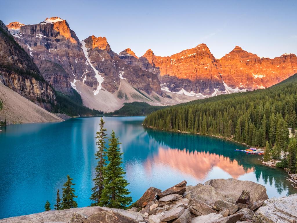 Crystal blue lake in the foreground with a sun kissed mountain range in the distance