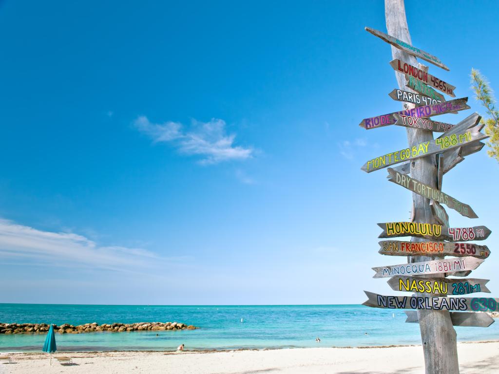 Key West, Florida, USA with the mileage signpost on the beach on a sunny day.