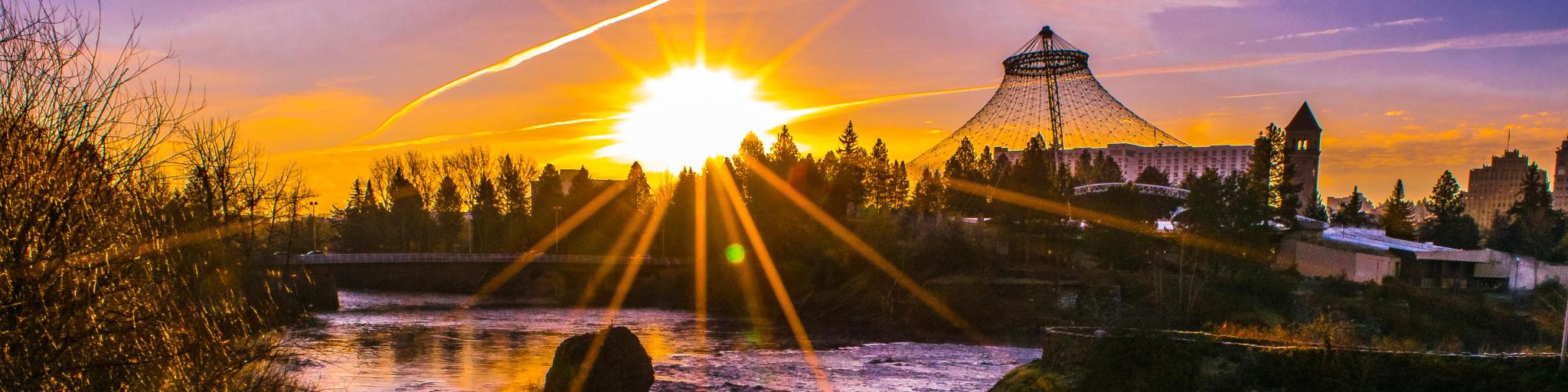 Orange sunrise over the river and trees in Spokane