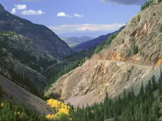 Million Dollar Highway running through the mountains in the San Juan Forest in Colorado with a blue sky above