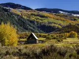 Panorama showing landscape with brilliant fall colors along road to Capitol Peak near Aspen Colorado on sunny autumn afternoon