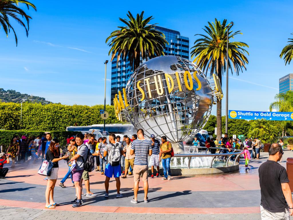 Tourists standing in front of the Universal Studios globe in LA on a sunny day