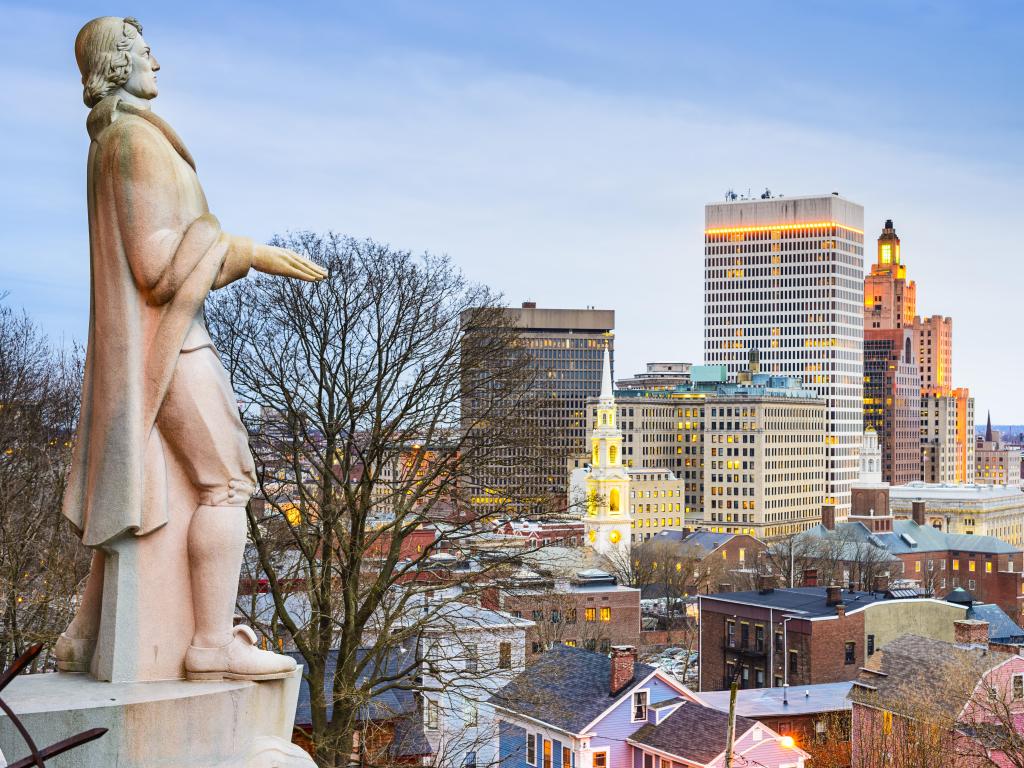 Providence, Rhode Island city skyline from Prospect Terrace Park as the sun sets with the monumental statue of the city's founder, Roger Williams, facing the buildings.