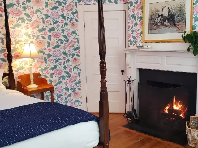 Cozy interior of a hotel bedroom with a fit-up fireplace and bed in view