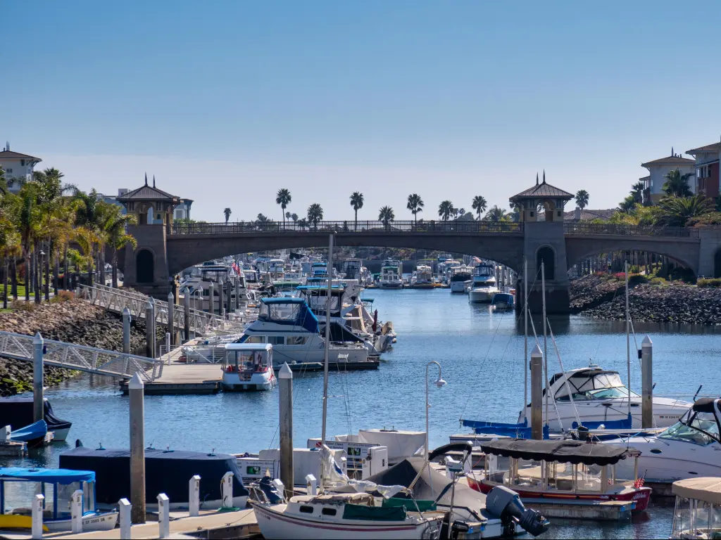 Marina in Oxnard, California, with yachts, palm trees and a bridge crossing the waterway