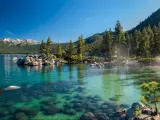Clear emerald water with rocks, pine trees and mountains at Sand Harbor SP, Lake Tahoe, Nevada