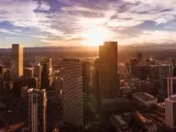 Panoramic aerial shot of the Denver skyline in Colorado at dusk, with wispy clouds drifting across the setting sun