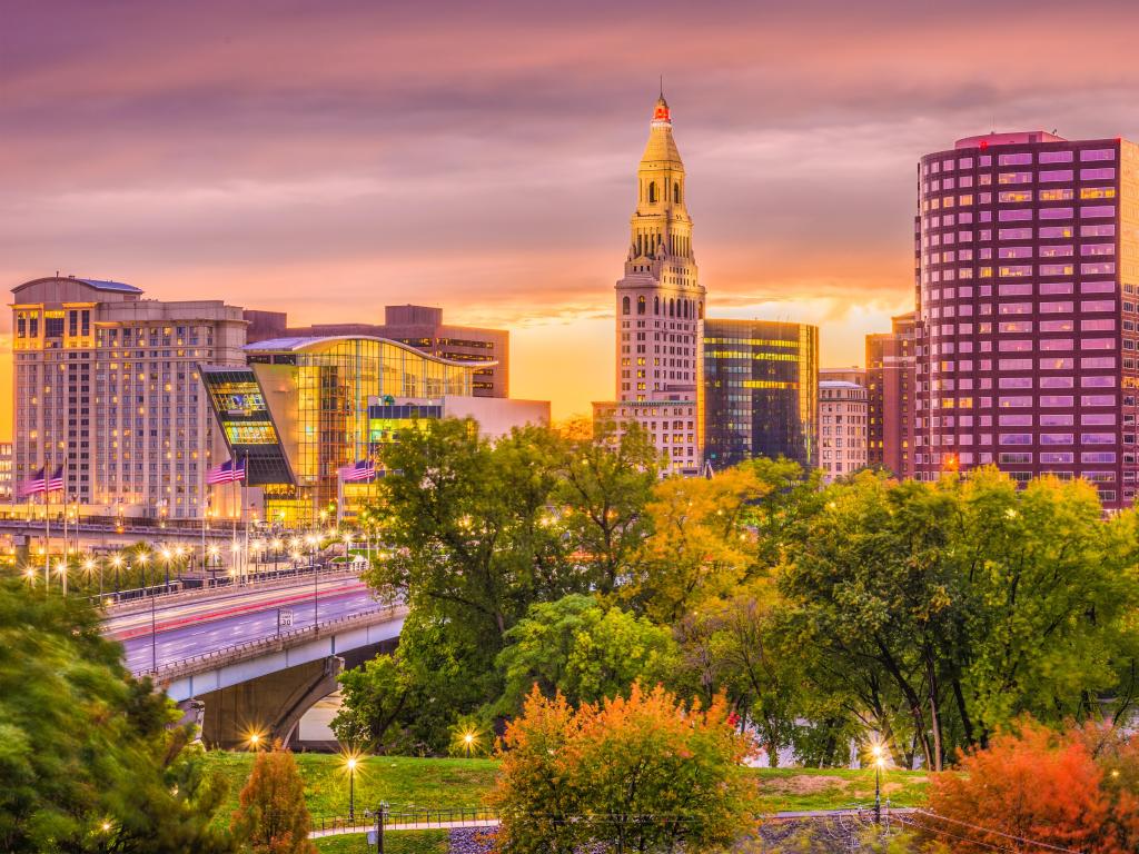 Hartford, Connecticut, USA with the downtown skyline at dusk in early autumn and trees in the foreground.