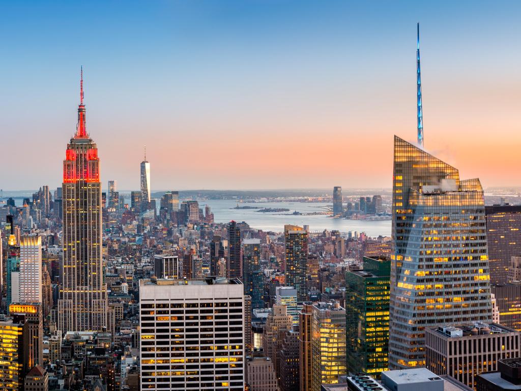 Aerial view over New York City at sunset. The Empire State Building is colored in red to honor the New York City Fire Department (FDNY).
