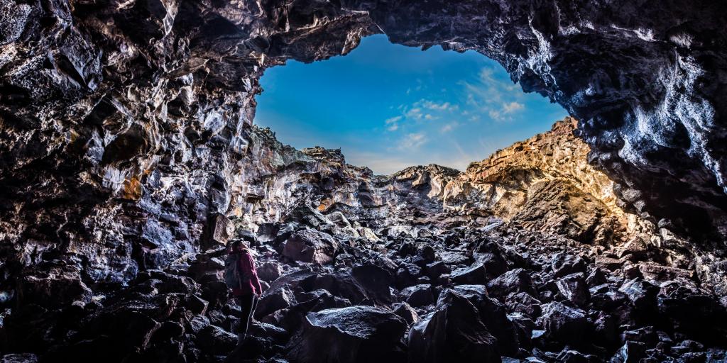 A woman climbs through the Indian Tunnel at Craters of the Moon National Monument and Preserve in Idaho, USA