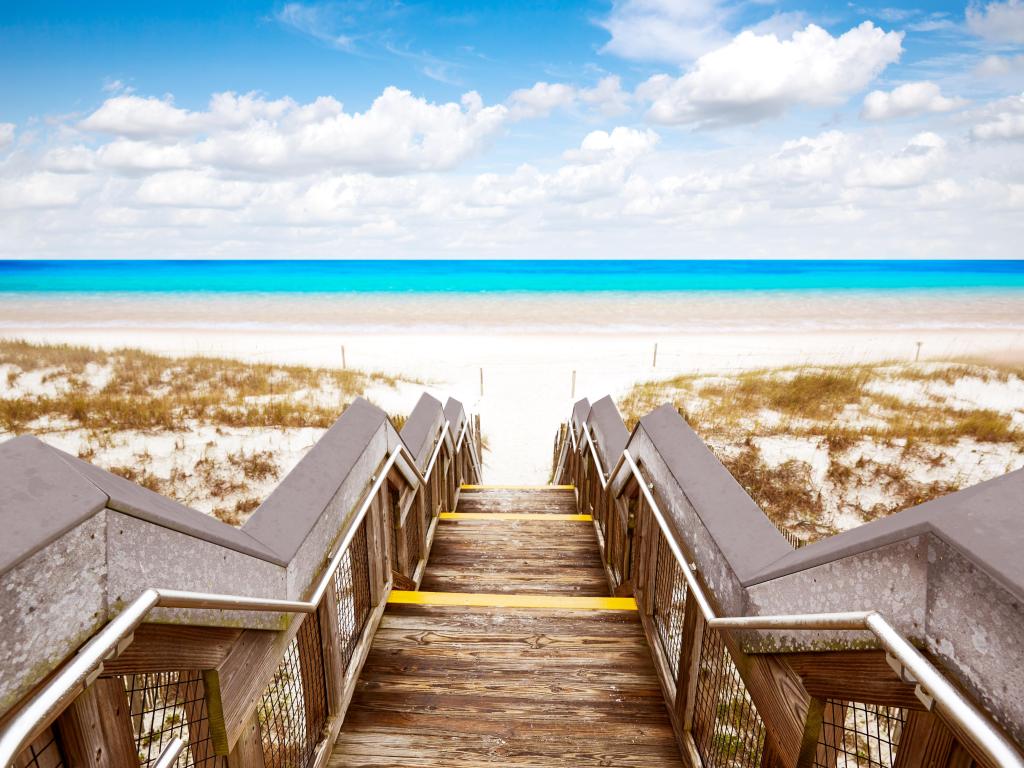 Henderson State Park, Florida showing wooden steps down to a golden beach with bright blue sea in the background.  