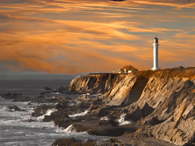 Dramatic sunset with lighthouse on a cliff in focus