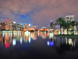 Orlando downtown skyline over Lake Eola at dusk with urban skyscrapers and lights.