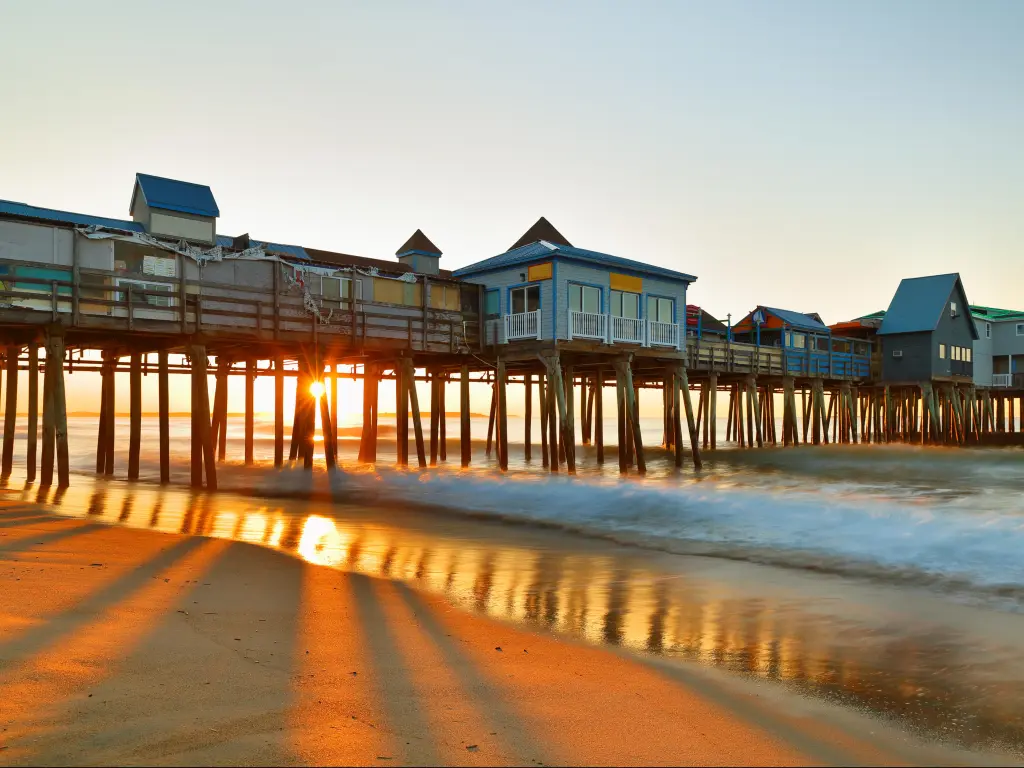 Old Orchard Beach, Maine USA with the iconic pier taken at sunrise, with the beach in the foreground and a calm sea.