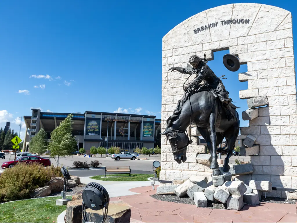 A stunning image of the "Breakin' Through" Bronze Statue at War Memorial Stadium at the University of Wyoming on a bright and sunny day.