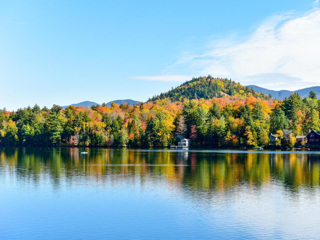 Lake Placid, New York, USA with Adirondacks Peak Fall Foliage in the background and the calm waters of the lake in the foreground taken on a sunny clear day. 