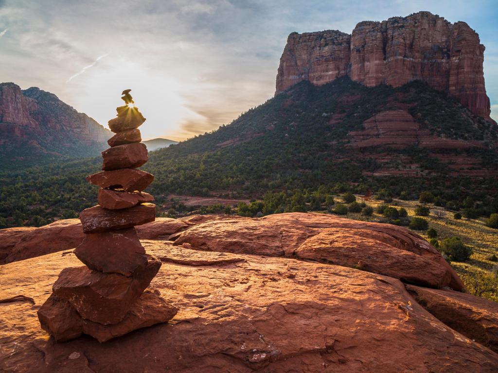 Sedona, Arizona, USA with a sunrise at Cairn Courthouse Rock, rocks stacked in the foreground and cliffs in the distance. 